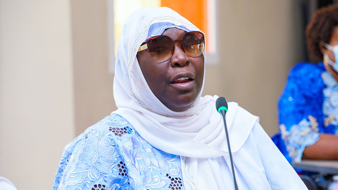 Woman wearing head covering and sunglasses speaking into a microphone
