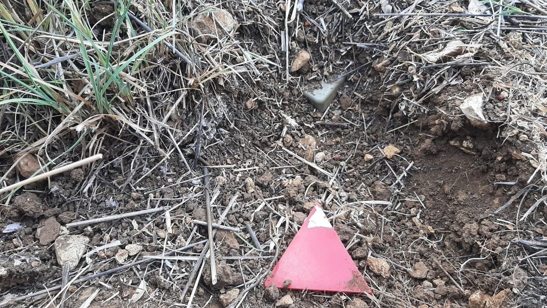 Israeli landmine in the dirt found in the village of Btater in the Aley district of Lebanon and marked with a red triangle by the HI demining team. 
