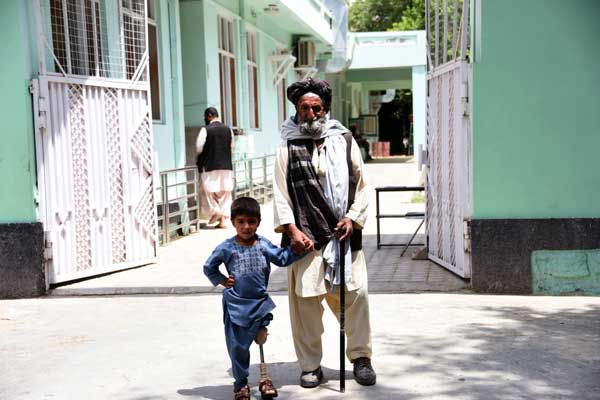 Sanaullah, 5, standing with his father outside the rehabilitation center in Kandahar. He lost his leg to a mortar in Afghanistan.