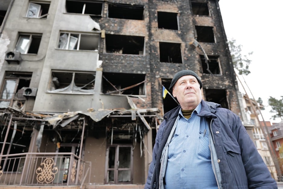 A man stands next to houses destroyed by armed violence in Irpin, Ukraine. 