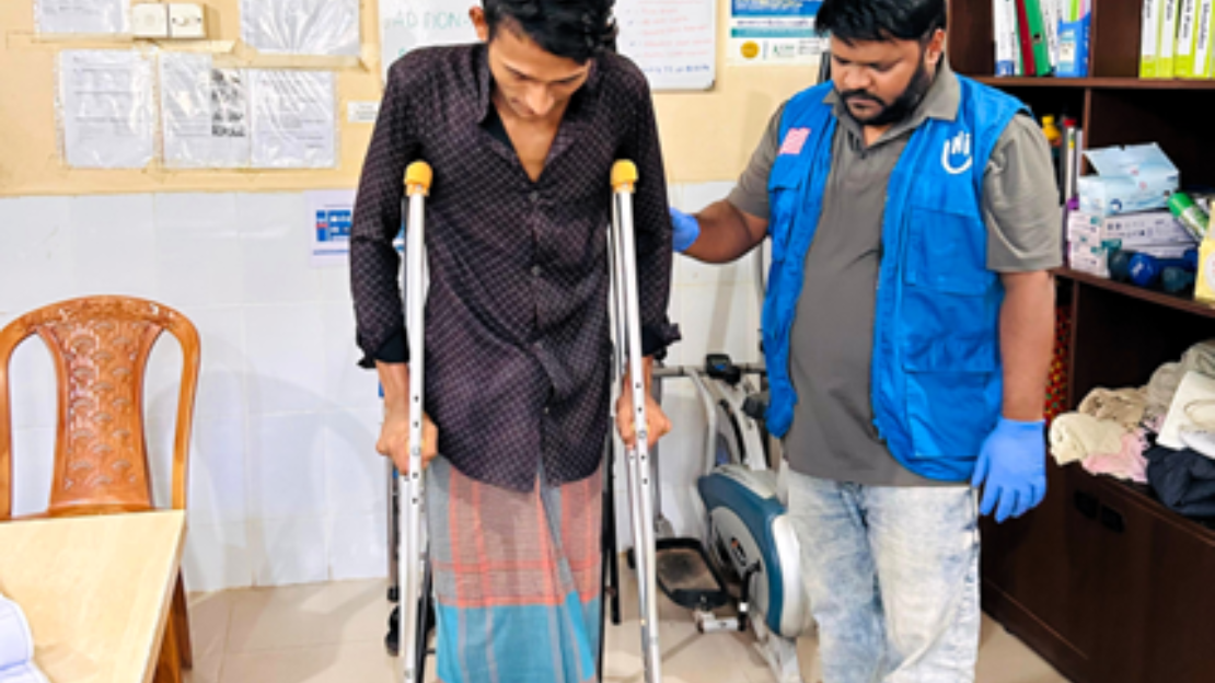 Karim is receiving training on an assistive device and practicing walking