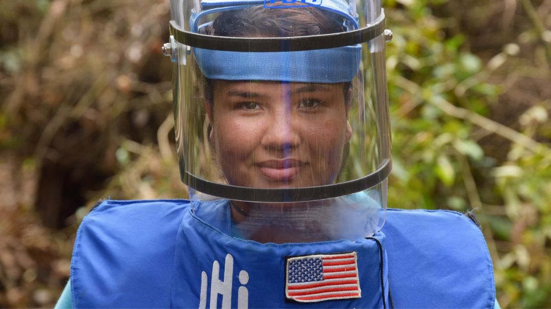 A Colombian woman wears a face shield and blue protective vest with HI and American flag patches on it