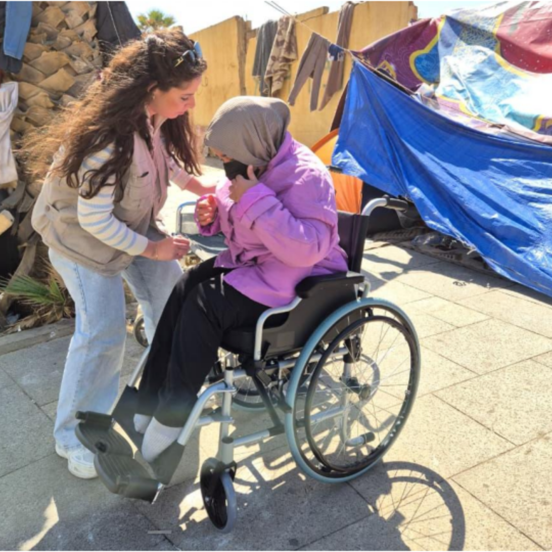 An HI field staff member assists a person with a disability during the distribution of assistive devices in Beirut, Lebanon. © HI/Lebanon Team; }}