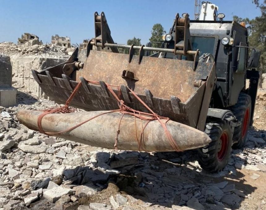 A bomb is removed from rubble by a heavy equipment operator in Syria