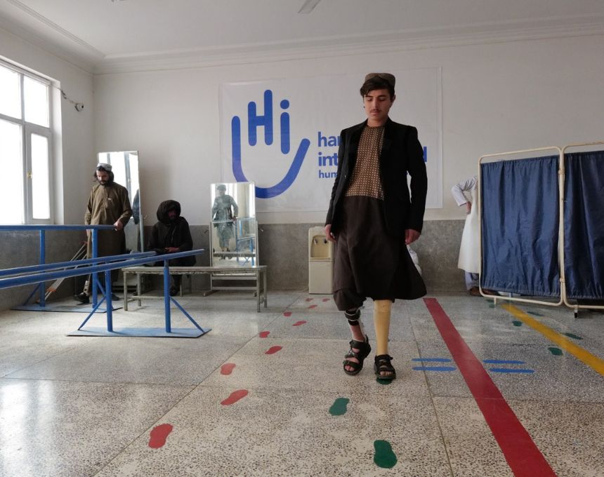 A young man wearing an artificial leg walks over marks painted on the floor of a rehabilitation center in Afghanistan