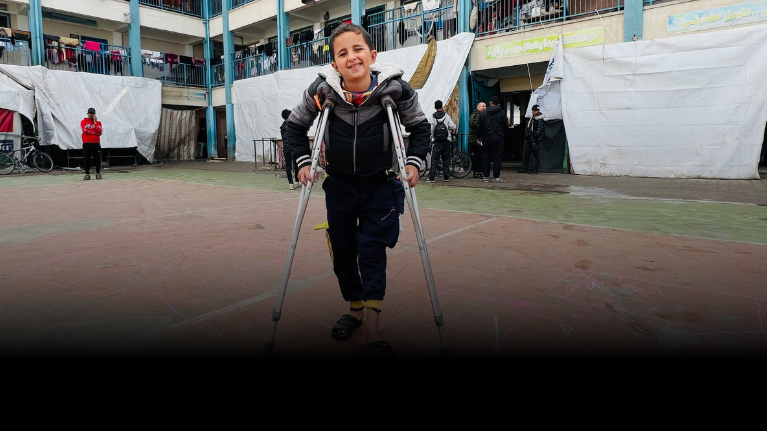 A boy with crutches smiles
