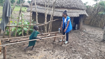 Young child using parallel bars to practice his rehabilitation exercises with HI specialist