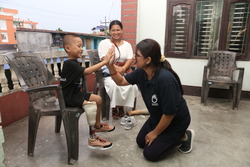 A young boy with a prosthetic leg and his P&O specialist doing a high five after the new prosthesis was fitted. Woman sitting behind them, smiling