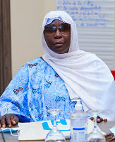 Woman wearing head covering and sunglasses behind a desk