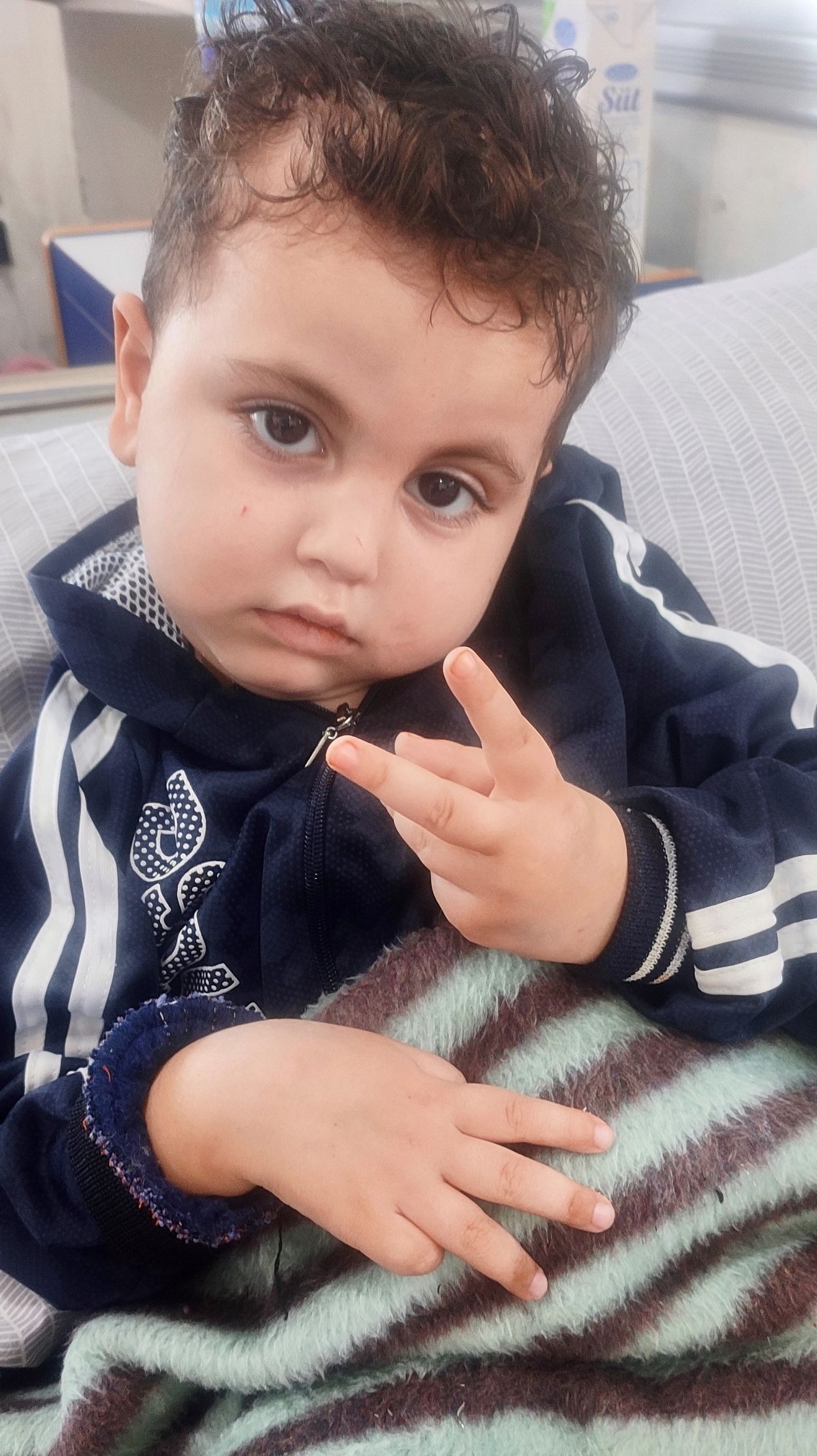 Close up portrait of a young toddler boy, holding up two fingers