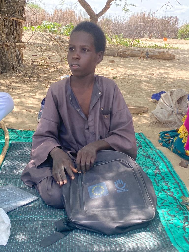 Mahamat sits with his backpack of school supplies. 