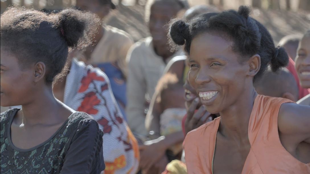 Woman smiles in a crowd as she listens to an information session about reproductive health. 