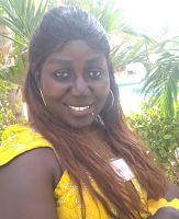 Woman smiling in front of palm trees, wearing yellow top and hoop earrings