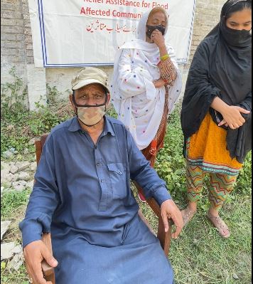 A man who lost his home in the floods sitting in a chair, wearing a face mask