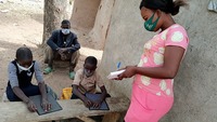 Twins sitting and learning braille from their teacher