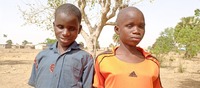 Twins standing in font of a tree