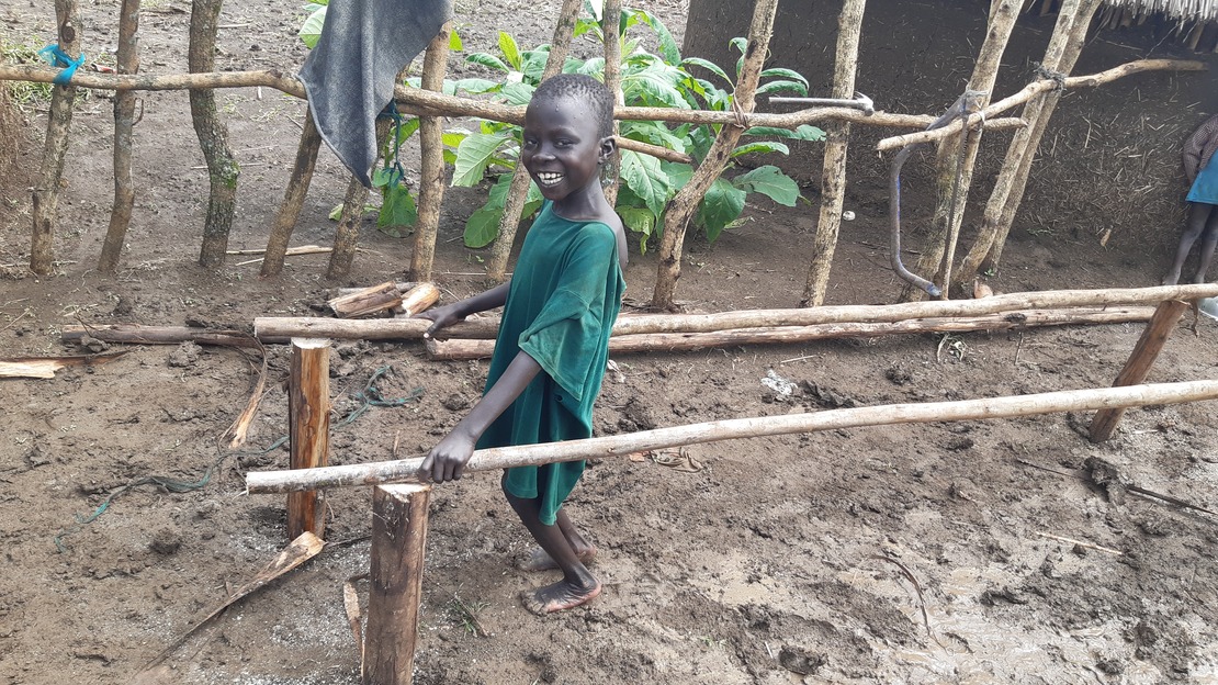 Young boy smiling while using parallel bars to practice his rehabilitation exercices