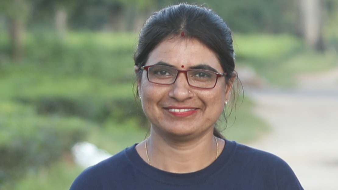 Nepalese woman with glasses smiling into the camera, wearing glasses and black shirt 