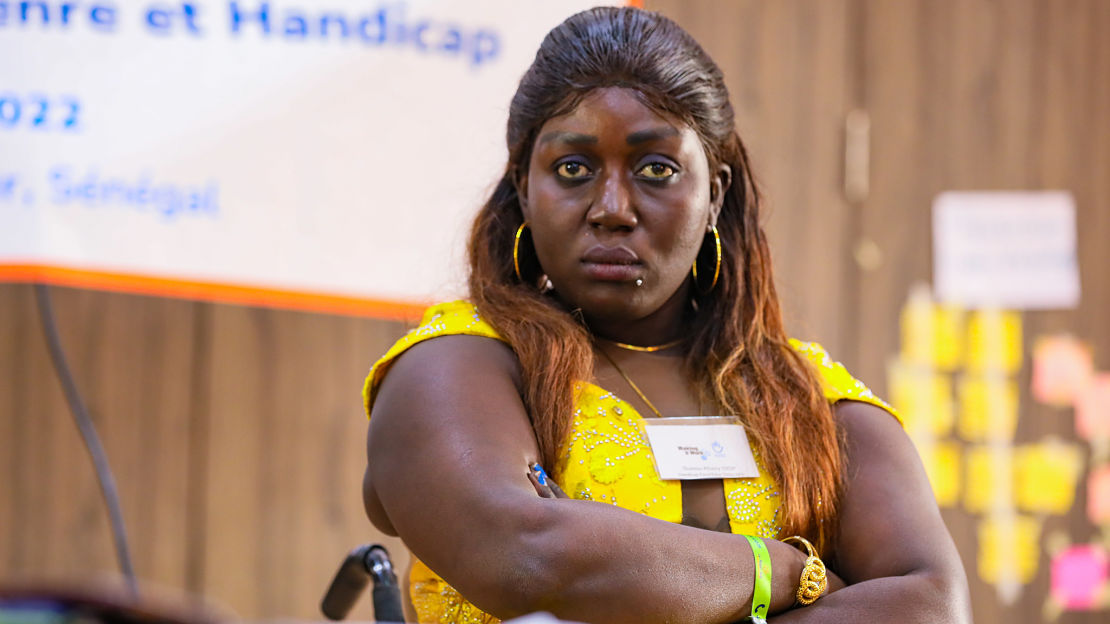 Woman at a workshop, seated in wheelchair, crossing her arms 