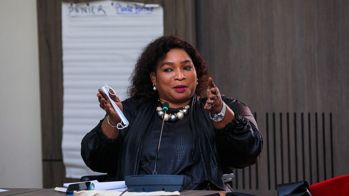 woman at a podium smiling and expressing herself with two hands pointed out 