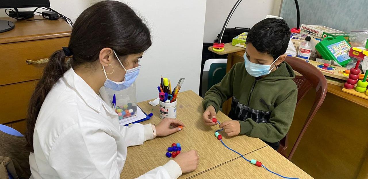 Mousawat's occupational therapist helps Ahmad complete his activity. 