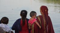 A woman and children look out onto a flooded village.