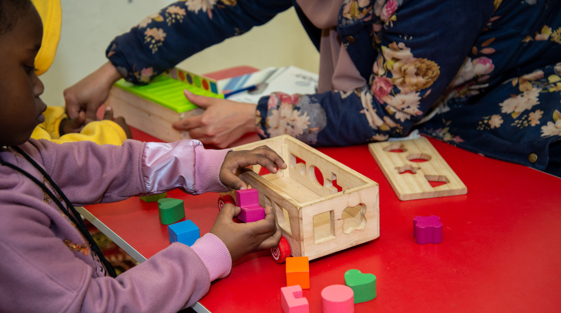 A Sudanese girl from the host community in Egypt takes part in a portage session aiming at expanding attention span and hand-eye coordination organized by HI’s Khotwat Project for Early Detection and Early Intervention.