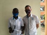 Disan, left, HI 3D Technician, with a finished 3D printed face shield, Ministry of Health, Kampala, Uganda 