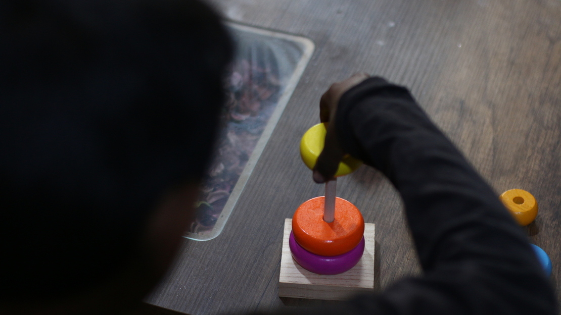 Photograph taken behind someone partaking in a support activity of circular building blocks. 