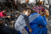A mother carrying her child on her back rests with others outside their earthquake-damaged house in Tijghicht, in the Atlas Mountains range, on September 14, 2023. A huge earthquake measuring 6.8 on the Richter scale hit central Morocco on September the 8th.. 