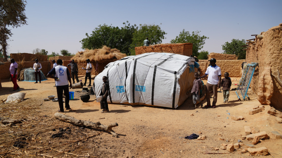 General view of the village with adults, children and a tent.