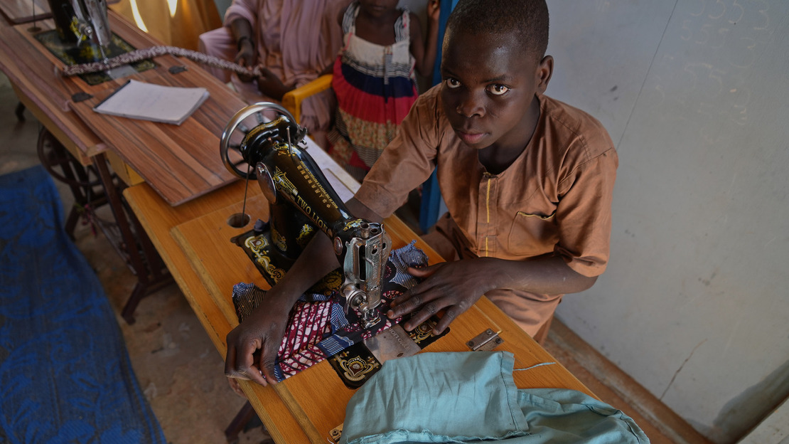 Overhead view of Hafizou Akilou sewing a piece of fabric on his sewing machine.