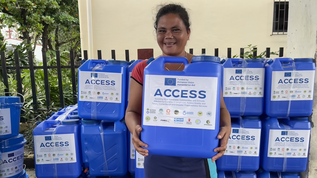 A young woman receives a jerrycan of water during a humanitarian aid distribution.