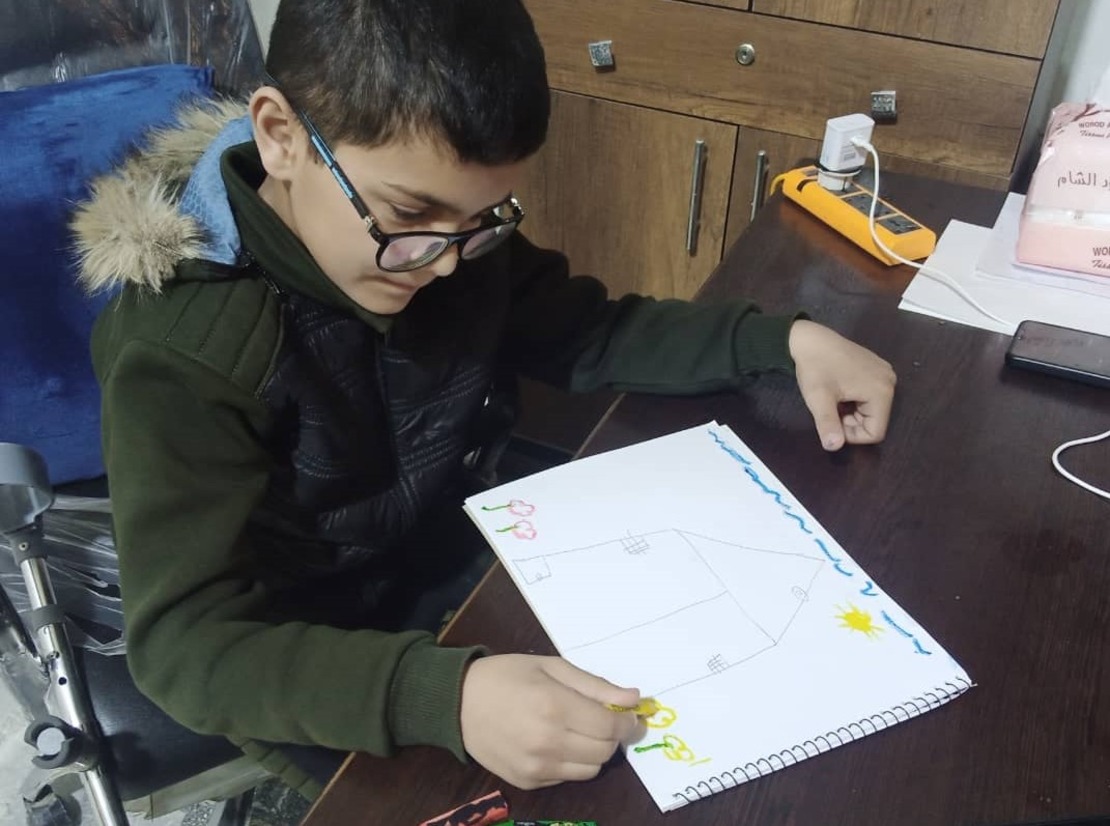 A little Syrian child draws a picture of a house and a sun 