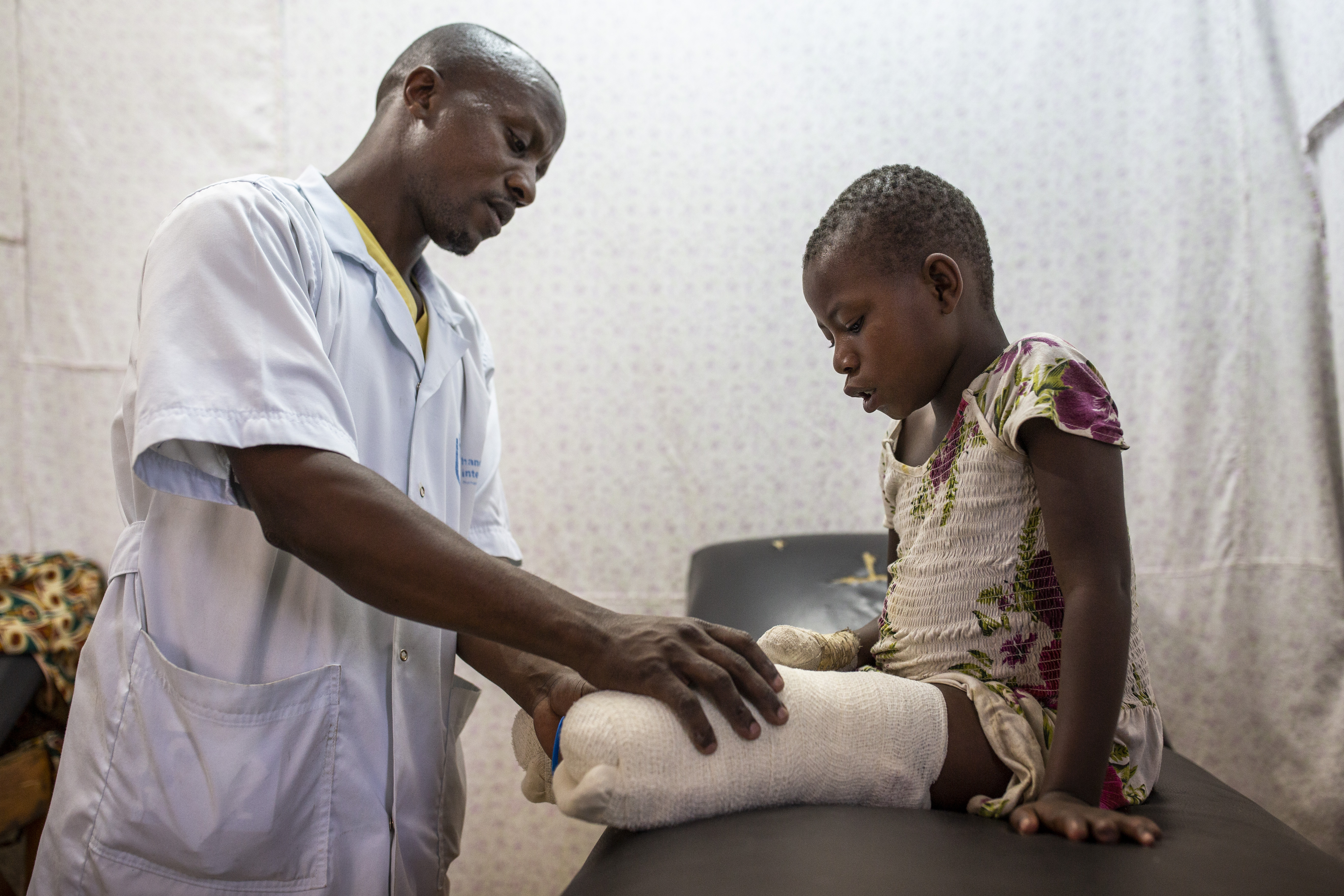 Kisubizo, a victim of the conflict in DRC, follows rehabilitation session with Jean Claude Karengane, an HI physio in Rutshuru.