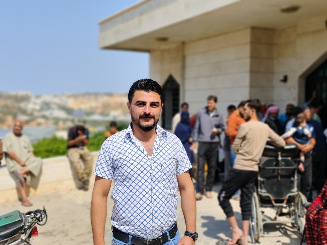 A man stands in front of a crowded hospital