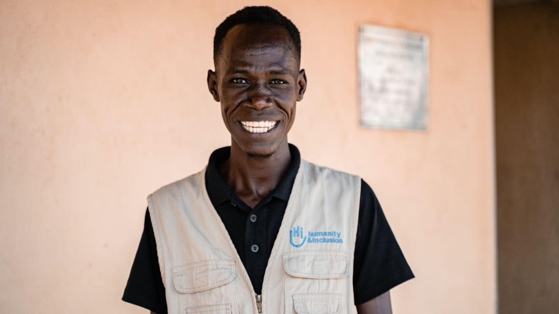 Portrait of Paul, looking at the camera and smiling. He's wearing a vest with the HI logo.