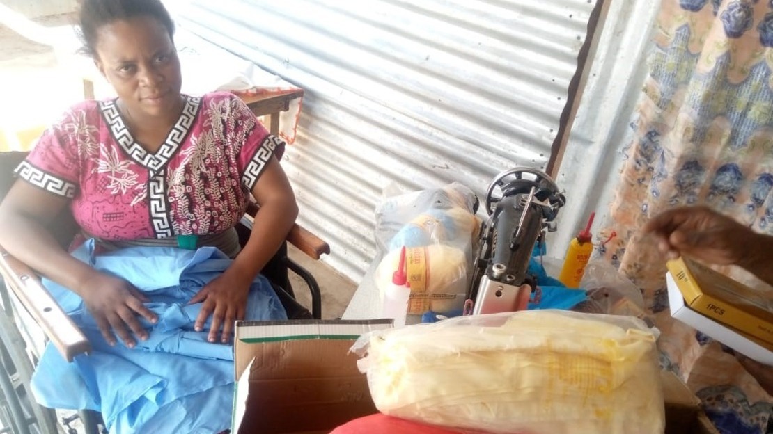 Women sitting in a wheelchair next to a table of sewing materials