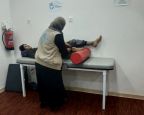 Teenage boy with amputated leg laying on a medical table being tended to by a HI specialist who stretches his leg