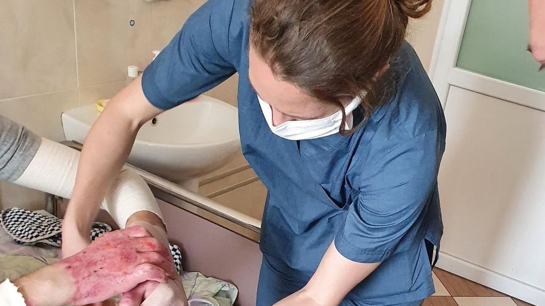 HI rehabilitation specialist, Violette, wraps bandages around a patient burned in an explosion. Lviv, Ukraine. 