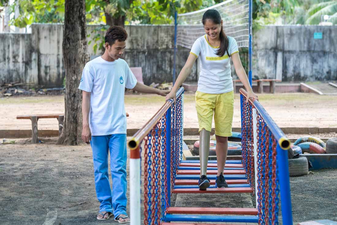 A girl with a artificial limb leg walks across an obstacle in HI' rehabilitation center, Cambodia