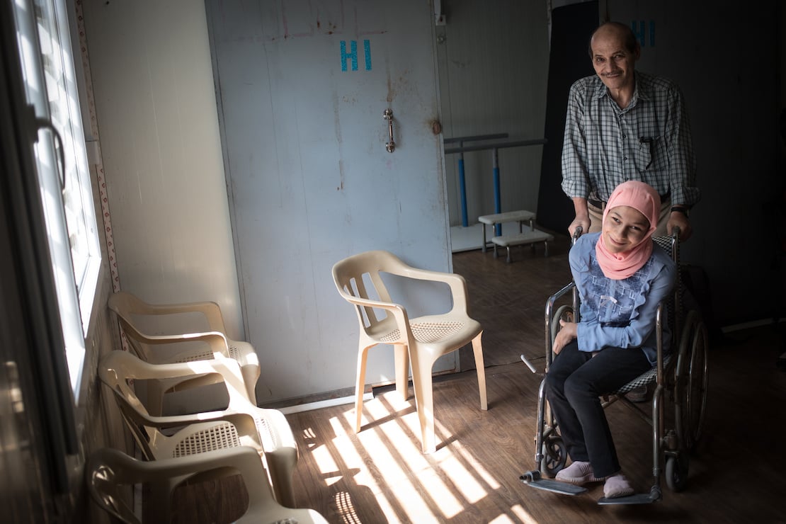 A father pushes his daughter in a wheelchair, Iraq