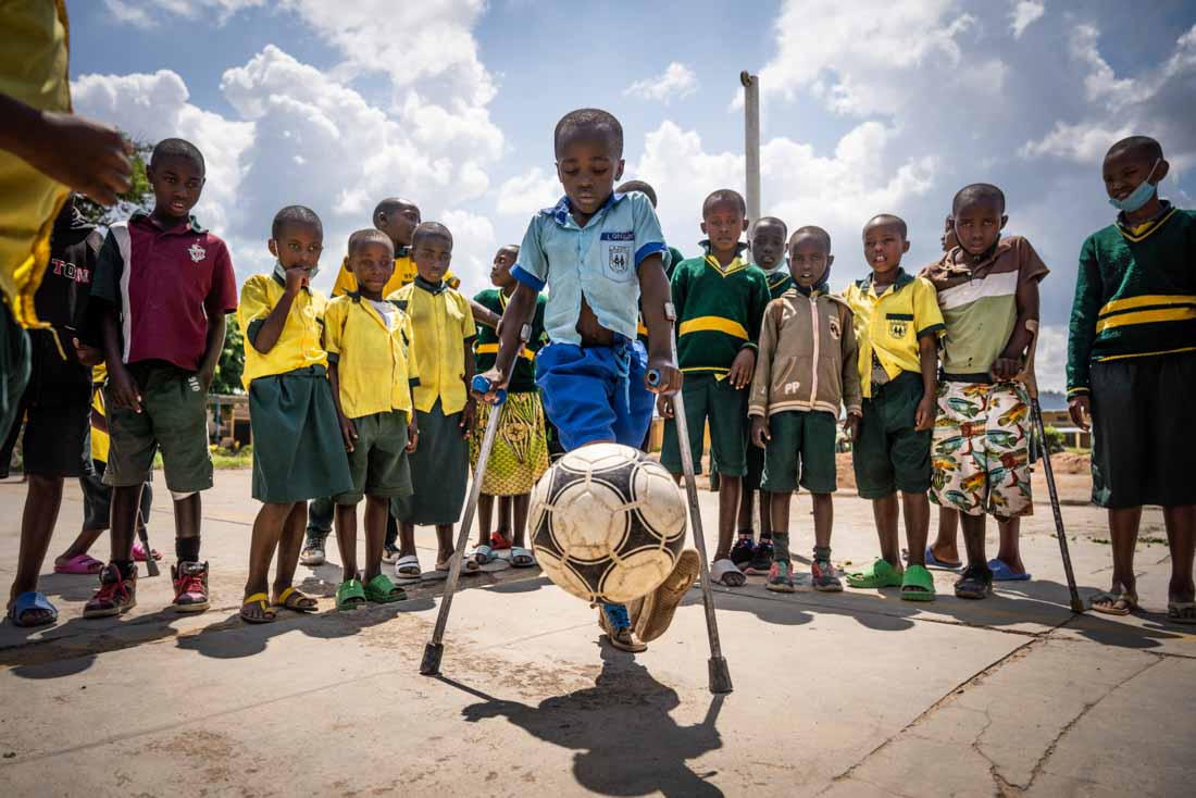 Longini playing football in the courtyard at school after he received his new artificial limb legs, Rwanda