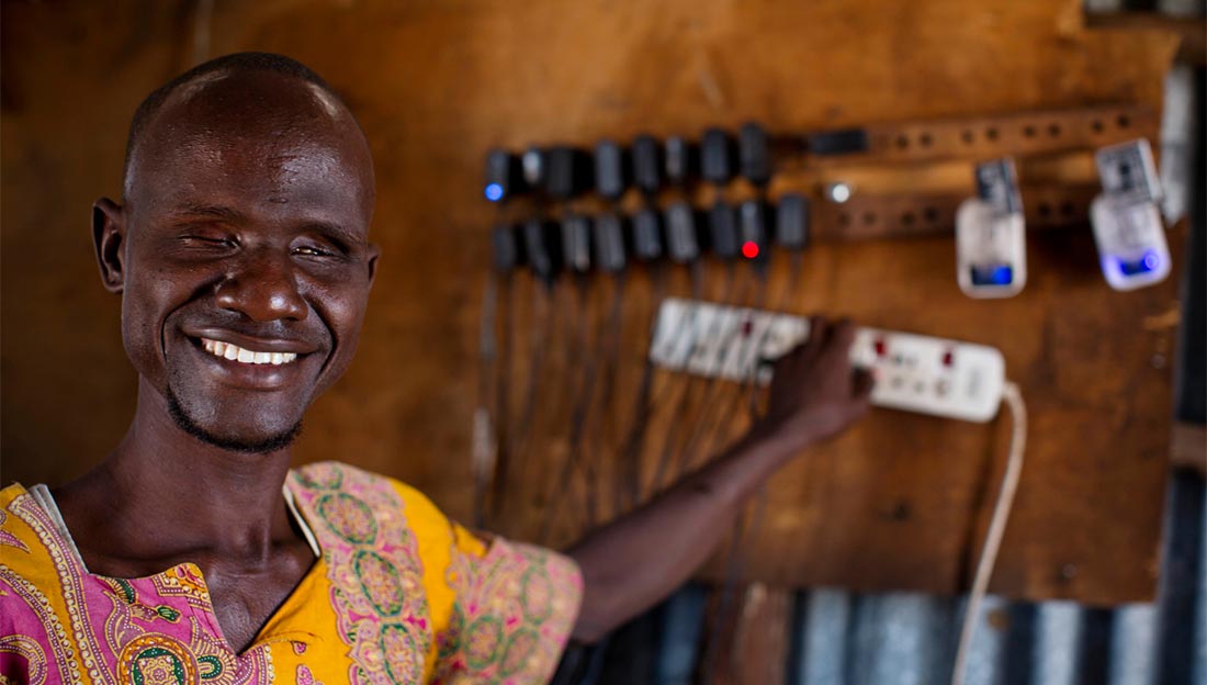 Ali, who is blind, charges phones in the shop he owns with his wife Abiba, who is also blind, in Kakuma Town, Kenya. Both Ali and Abiba are from Kakuma and have received support for their shop from Humanity & Inclusion.