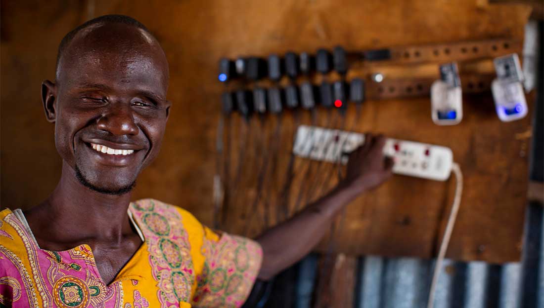 Ali, who is blind, charges phones in the shop he owns with his wife Abiba, who is also blind, in Kakuma Town, Kenya. 