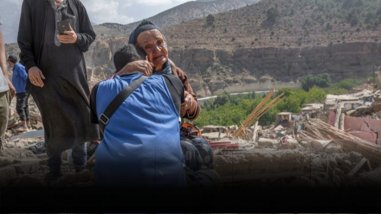 An aid worker hugs an elderly woman