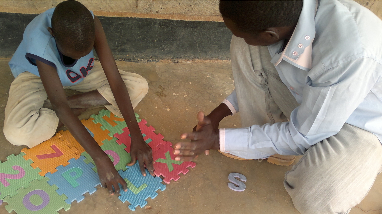 A child with his father doing puzzle during a psychomotor development session in the Dadaab camp, Kenya