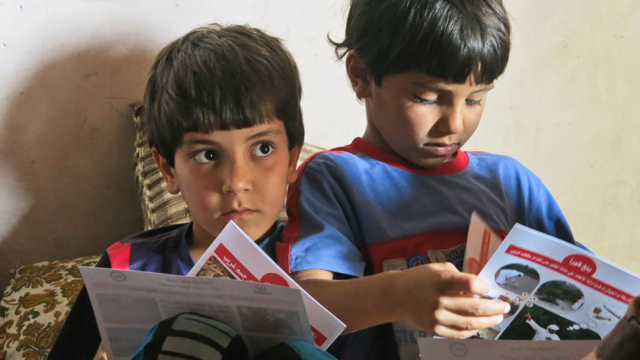 Two brothers look at the leaflets left by Handicap International’s team, at the end of a session.