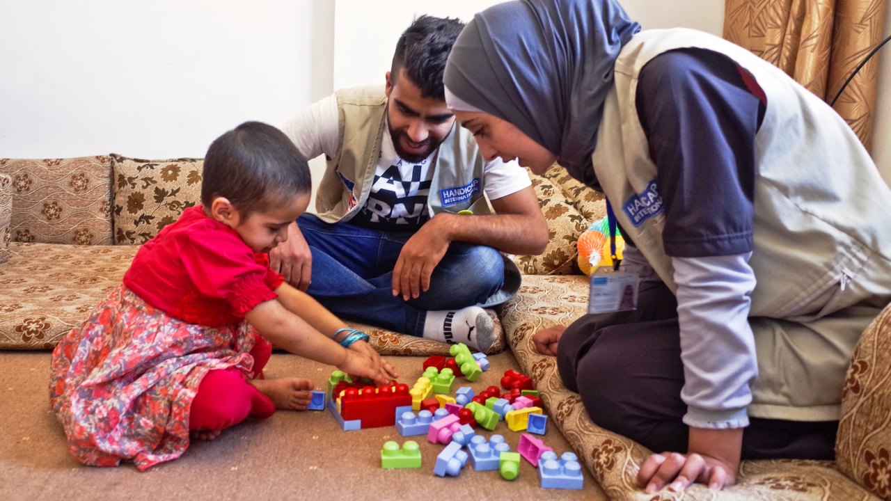 Huda plays with Handicap International staff Abood and Salam as part of a rehabilitation session.