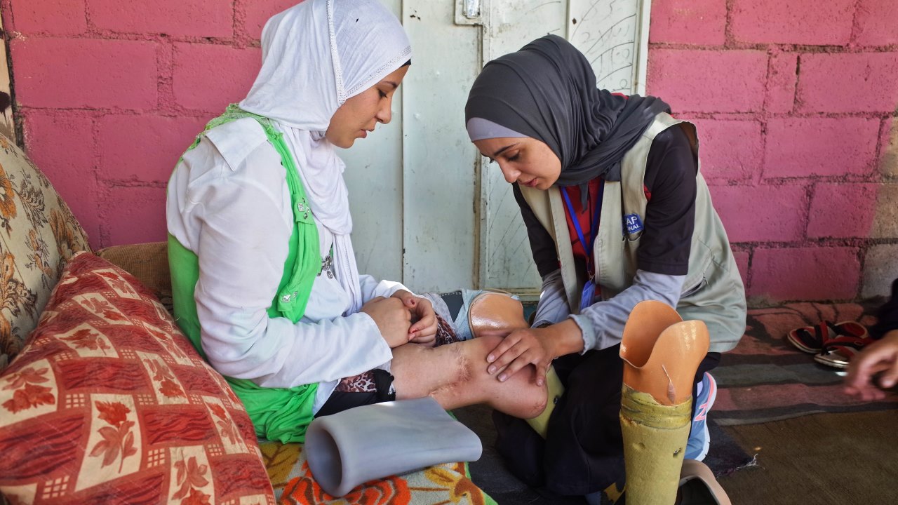 Salam has her legs checked by a Handicap International physical therapist